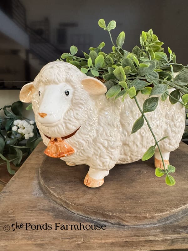 Vintage Lamb Planter with greenery on wooden riser