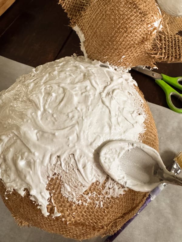 adding spackling to burlap covered DIY lambs with a spoon