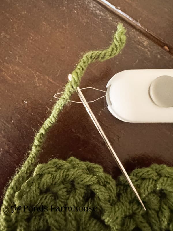 thread needle with yarn to secure the end of the yarn to the doily