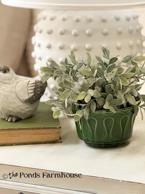 vintage green Floraline McCoy planter with greenery next to bird and lamp on side table