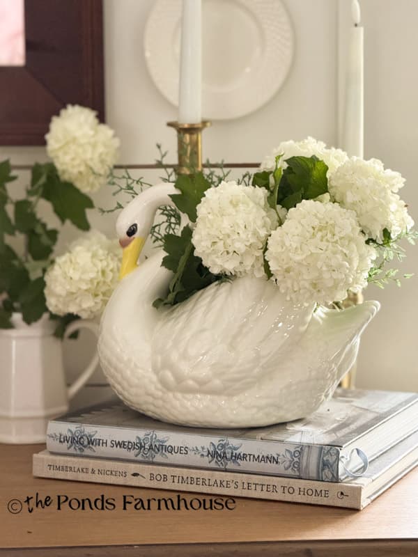 Vintage Swan Planter with snowball blooms on entry table
