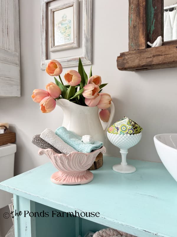 Vintage pink planter filled with bathcloths on bathroom countertop
