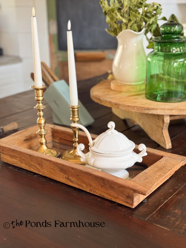 Mirrored wooden tray with vintage brass candlesticks and tureen on kitchen island