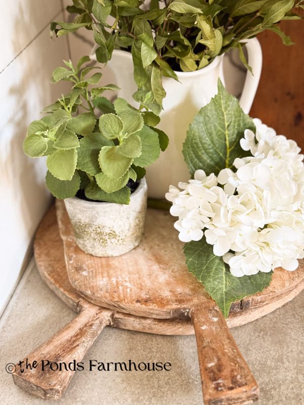 vintage breadboards stacked on kitchen island with plants