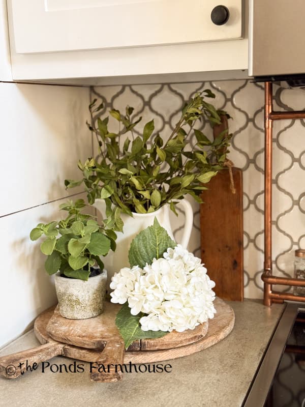 vintage breadboards stacked on kitchen island  decorated with plants & cutting booard