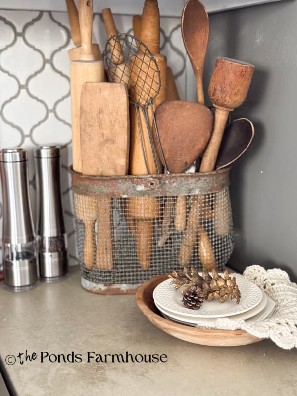 wire basket filled with wooden kitchen utensils on concrete kitchen countertops