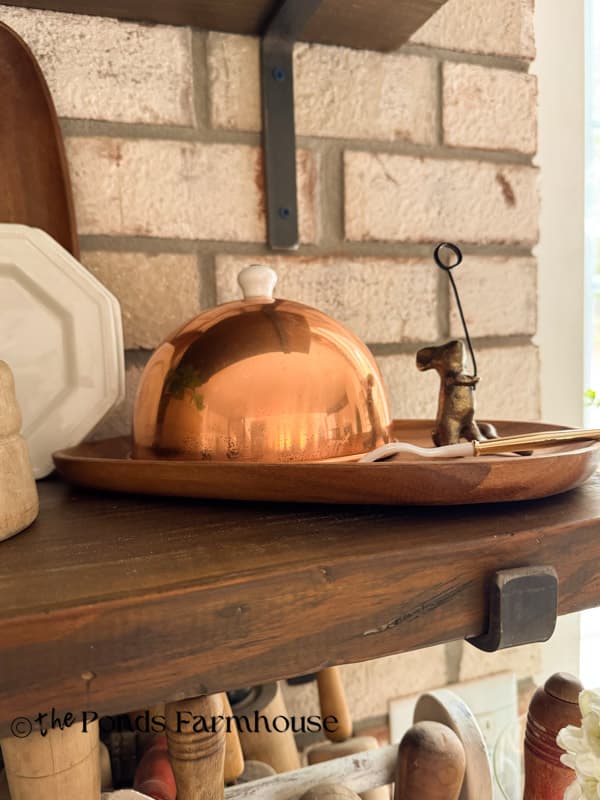 Vintage copper dome on wooden tray for serving cheese.
