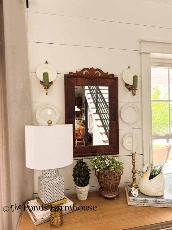 brass wall candle scones that hold plates on entry wall around antique mirror.