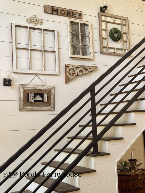 Gallery Wall in stairway with old windows, framed wall paper stamps, and salvaged iron art.