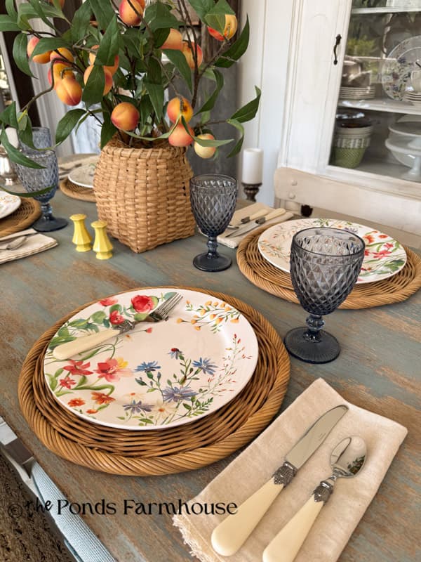 Summer tablescape with floral dishes, bone cutlery,and blue water goblets