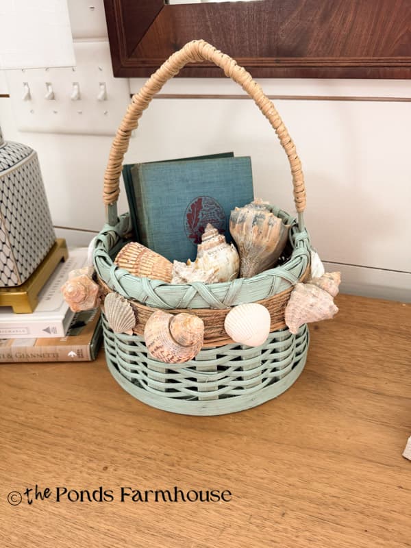 upcycled thrifted basket with seashells filled with books and seashells
