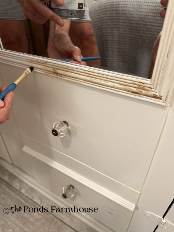Adding dark wax to enhance the details of the armoire