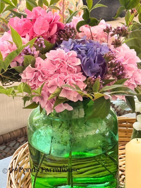 green glass canister filled with fresh hydrangea pink & blue blooms