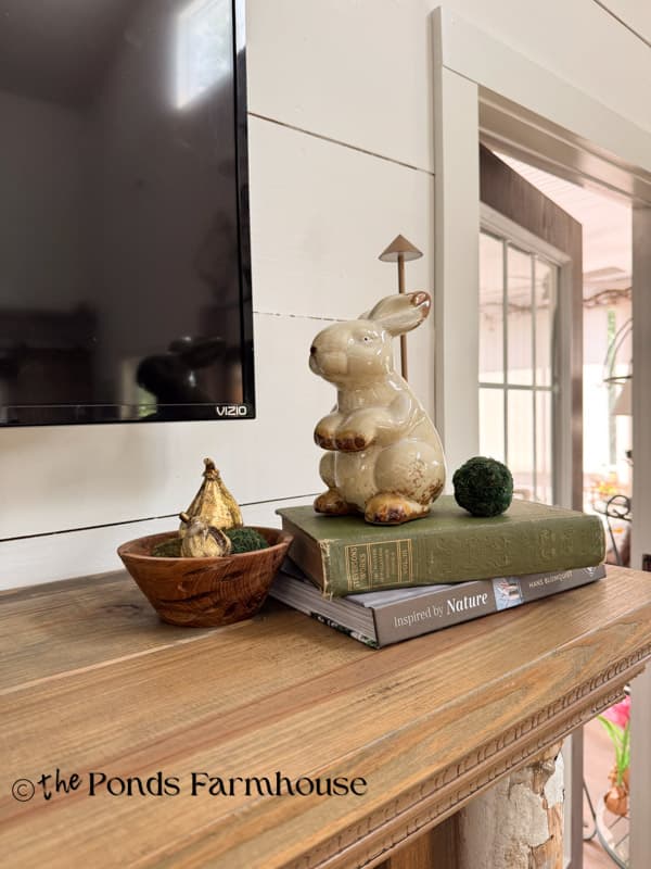 Summer moderately decorated mantel with vintage bunny, LED lamp, wooden bowl with moss balls and gold figs