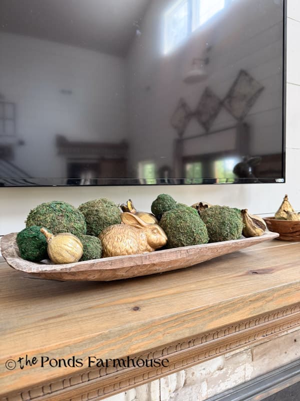 moderately decoard mantel for summer with dough bowl filled with moss balls, gold bunny and gold figs