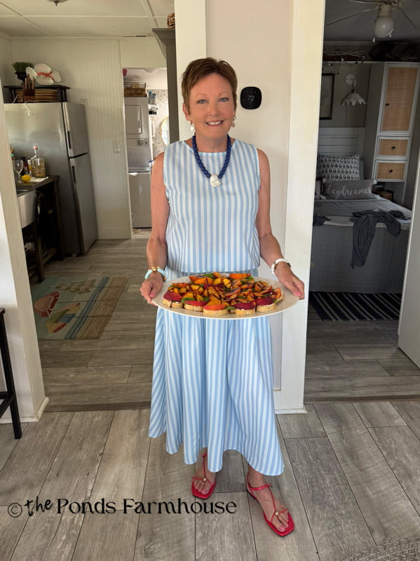 Rachel with blue & white dress, holding peach appetizer for 4th of July celebration