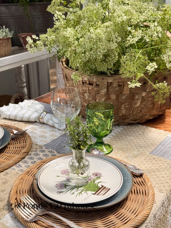summer garden party table with thrifted botanical herb dishes and vases of fresh herbs