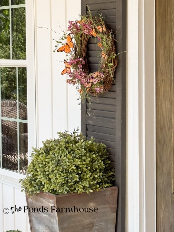 artificial boxwood in planters for wilt-proof summer porch with butterfly wreath on shutter