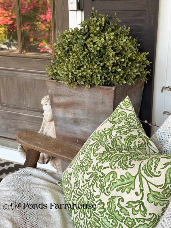 green outdoor pillow cover with faux boxwood planter