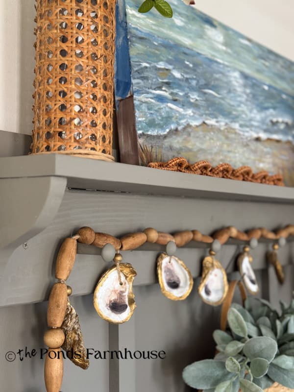 Oyster shell garland & rattan vase with beach painting on Accent wall shelf