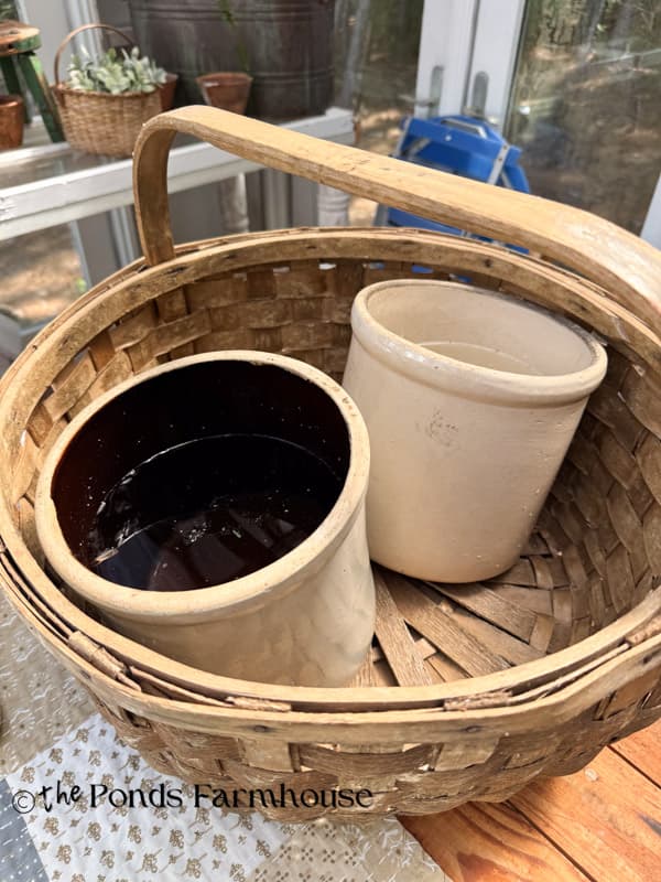 two crocks filled with water in oversized thrifted basket for flower arrangement
