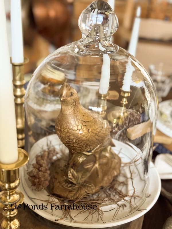 Gold pheasant on white plate with glass cloche for dining table centerpiece