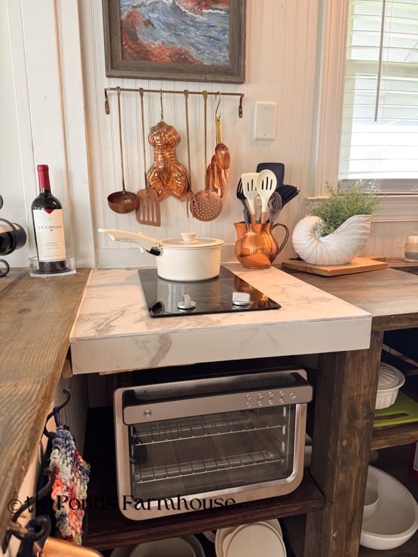 Updated small beach cottage kitchen with a space-saving two-burner stove, air fryer/oven, and open cabinets.