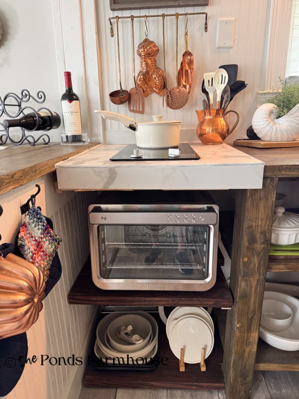 Updated small beach cottage kitchen with a space-saving two-burner stove, air fryer/oven, and custom open cabinets.