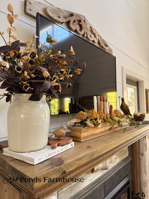 full view of cozy fall mantel decor with crock, DIY candlestick holder and pheasant for autumn decorations