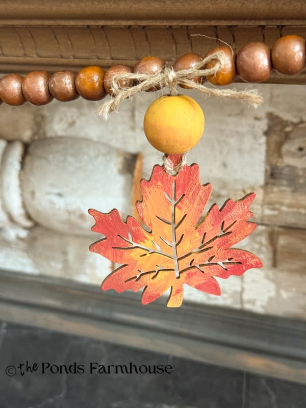 painted wooden leaf tied to bead garland with jute bow
