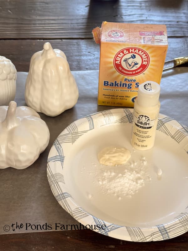 Mixing paint with baking soda to paint Dollar Tree Pumpkins
