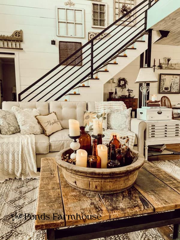 Wooden Bowl with vintage amber bottles and flicker candles on coffee table for fall home tour.