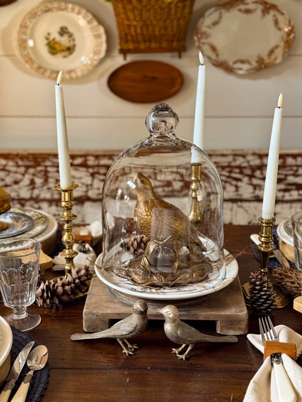 glass cloche with gold pheasant and brass candlestick holders