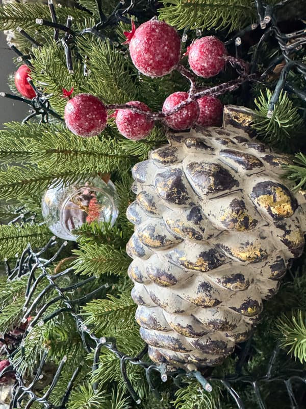 King of Christmas tree with pinecones, red berries, and DIY snow globes