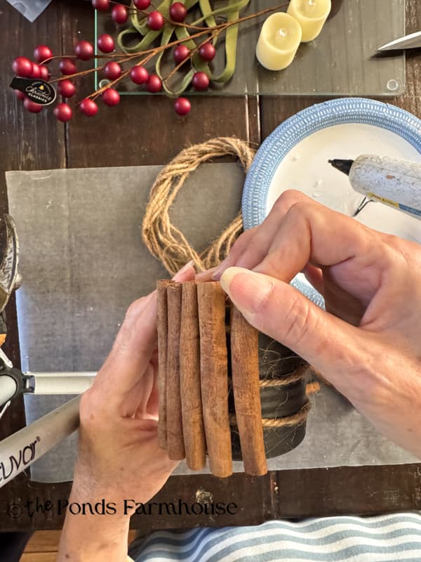 adding cinnamon stick to tin can by pressing into the hot glue