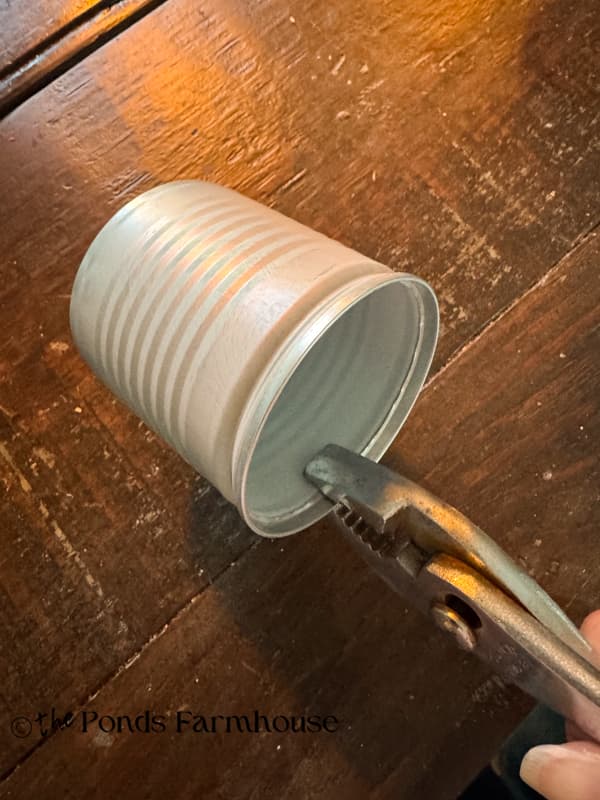 Bend the rim of the tin cans to flatten sharp edges.